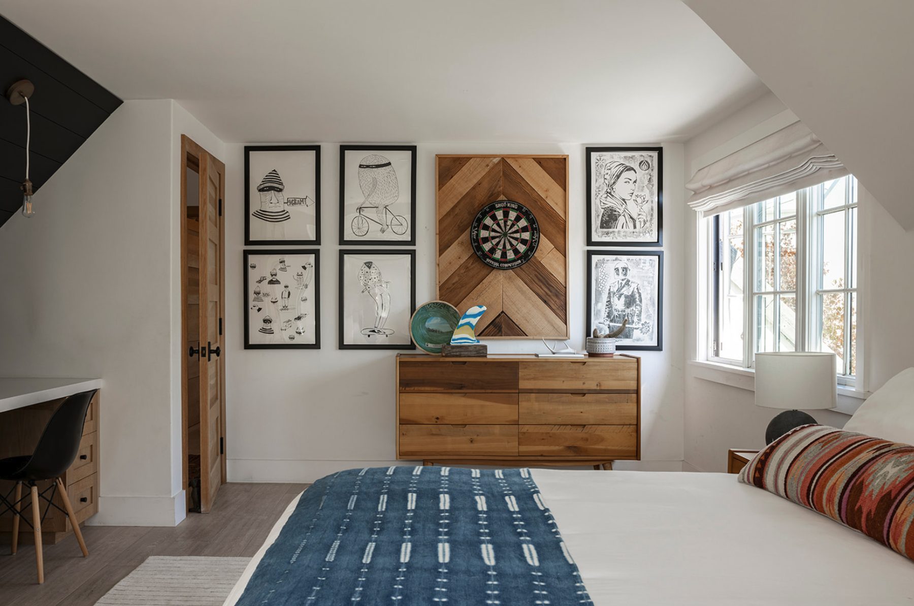 Atelier Azul bedroom with framed drawings, a reclaimed-wood dartboard panel and an indigo throw