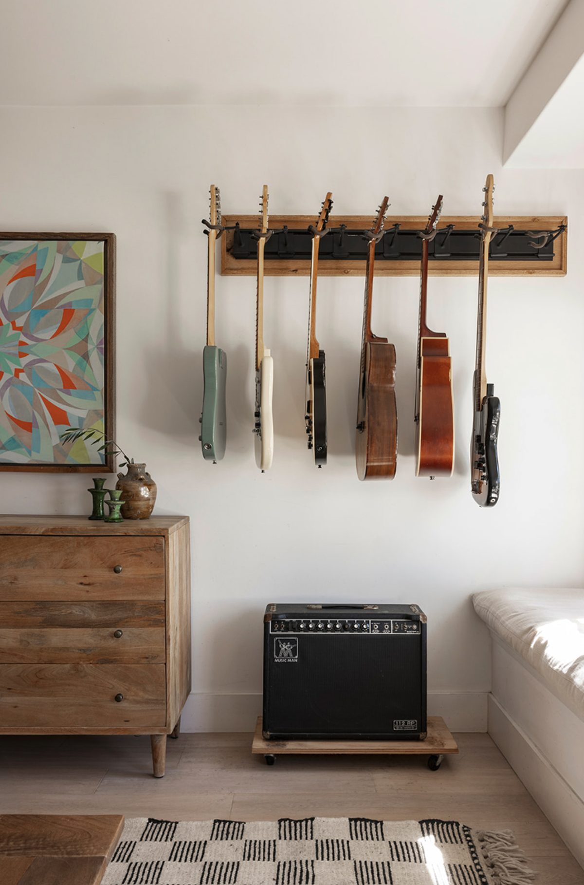 Atelier Azul music room with six guitars hung on a wood rail above an amplifier
