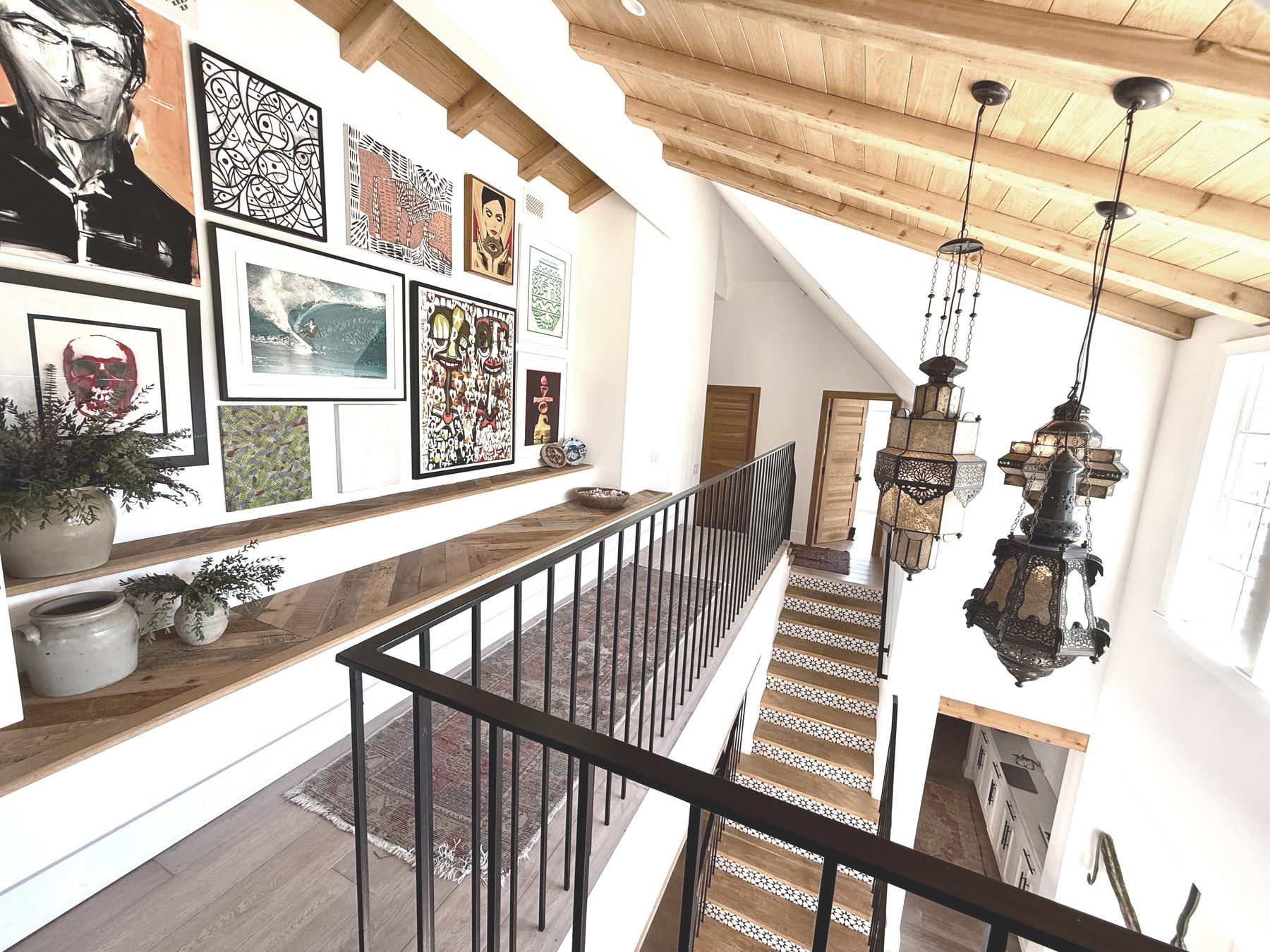 Atelier Azul upstairs landing with a gallery wall of framed art, Moroccan lanterns and a patterned-tile staircase