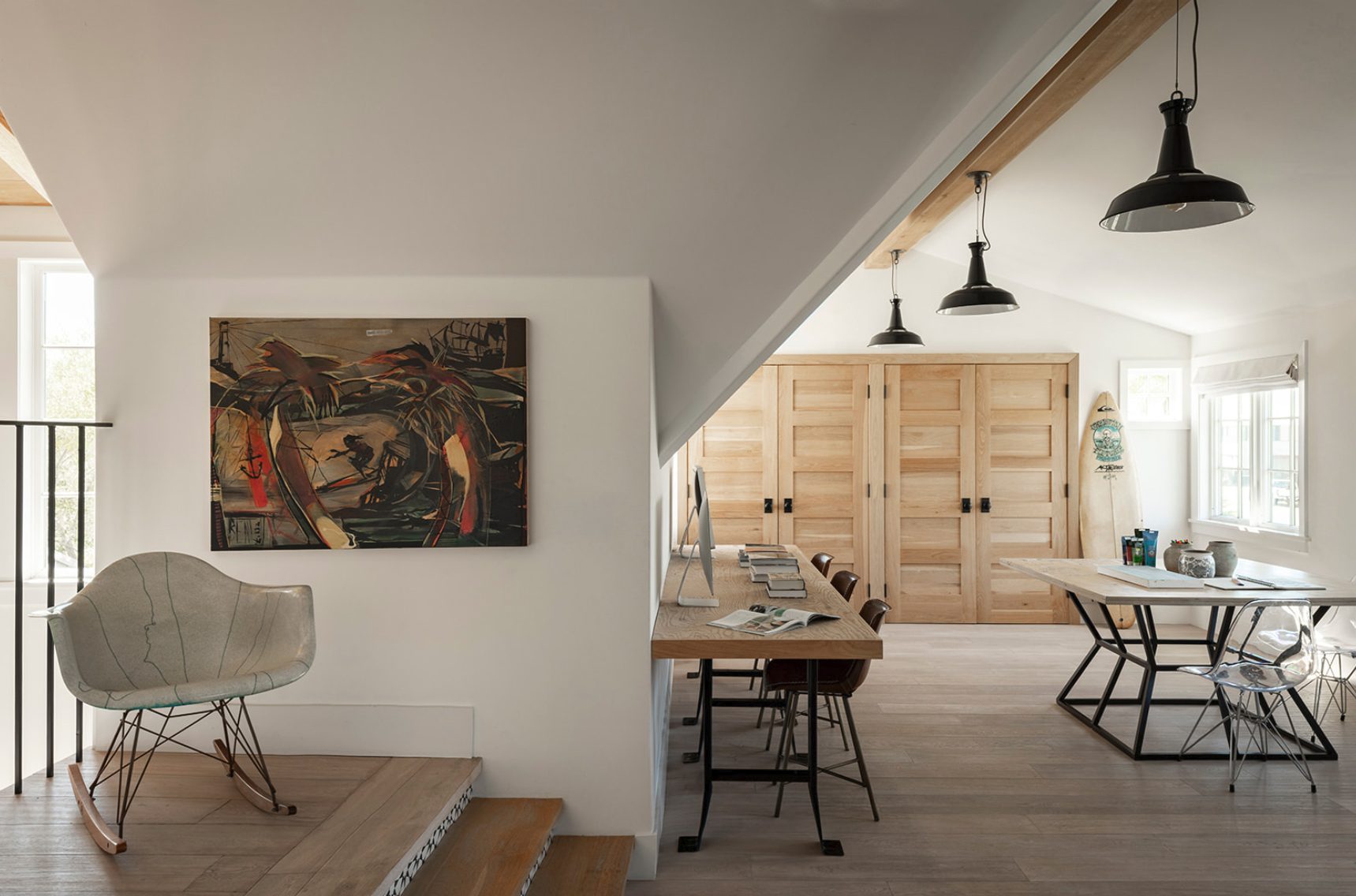 Atelier Azul attic studio with a long wood desk, black pendant lights, oak cabinet doors and a painting on the wall