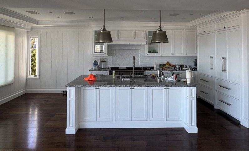 The kitchen before: dark floors and a grey granite island
