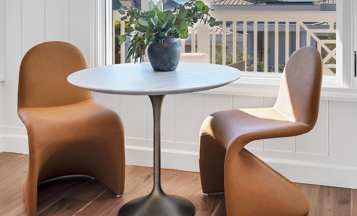 Breakfast nook with a round white table and two sculptural leather chairs