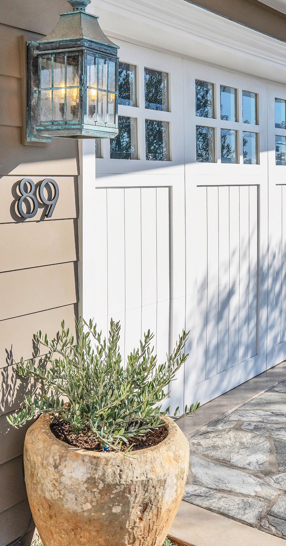 Front entry with a copper lantern and an olive tree in a clay pot