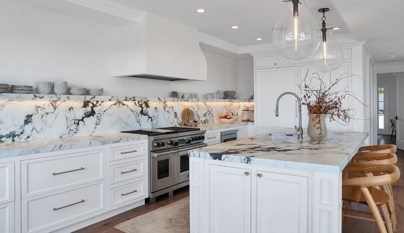 The kitchen after: white cabinetry, marble counters and a new range hood