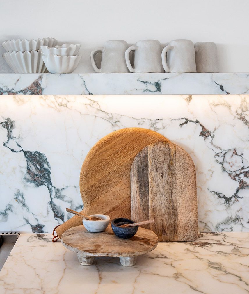 Marble counter and shelf styled with wood boards and ceramic pitchers