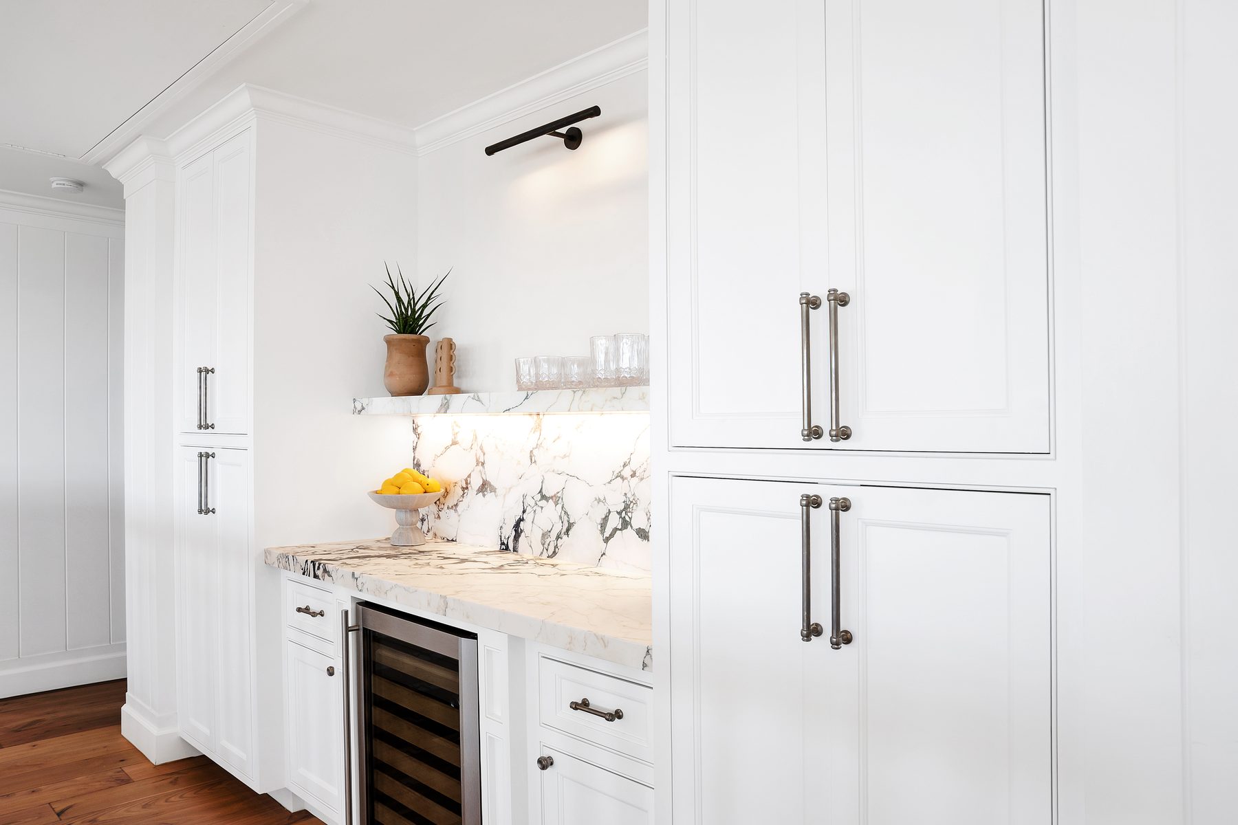 Built-in bar with white cabinetry, a marble counter and shelf, and a wine fridge