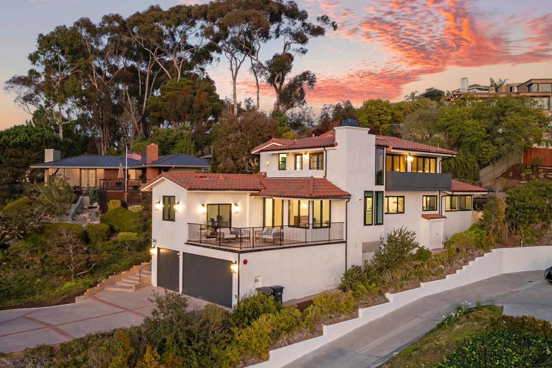 Vista Bahia exterior at sunset: a white hillside home with a clay tile roof and a wide terrace